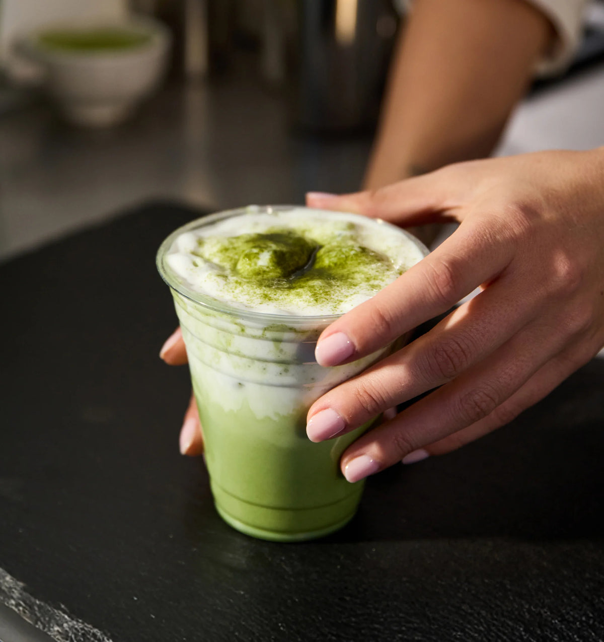 Person holding a cup of green matcha latte
